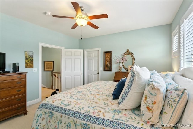 bedroom featuring baseboards, multiple windows, ceiling fan, and light colored carpet