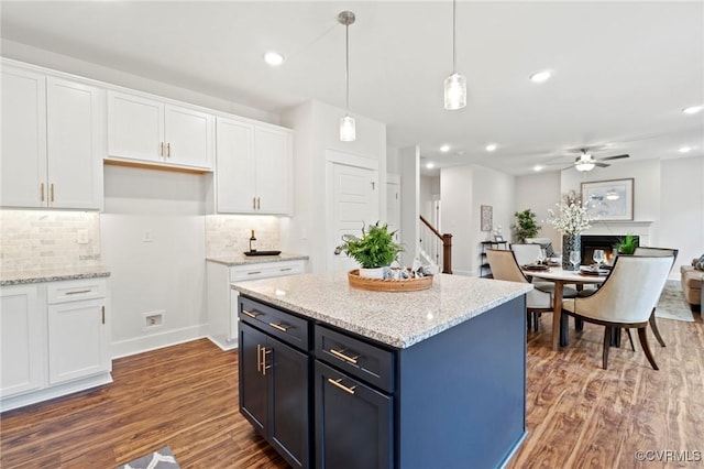 kitchen featuring white cabinetry, wood finished floors, hanging light fixtures, and tasteful backsplash