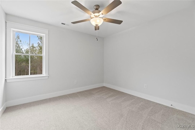 carpeted spare room with baseboards, a ceiling fan, and visible vents