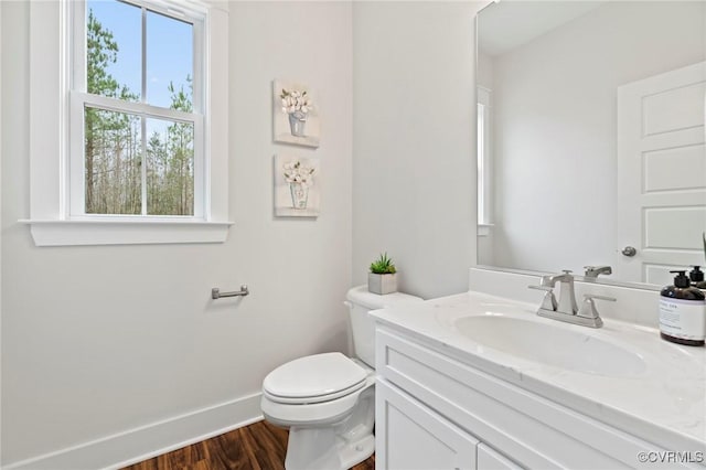 bathroom featuring vanity, baseboards, wood finished floors, and toilet