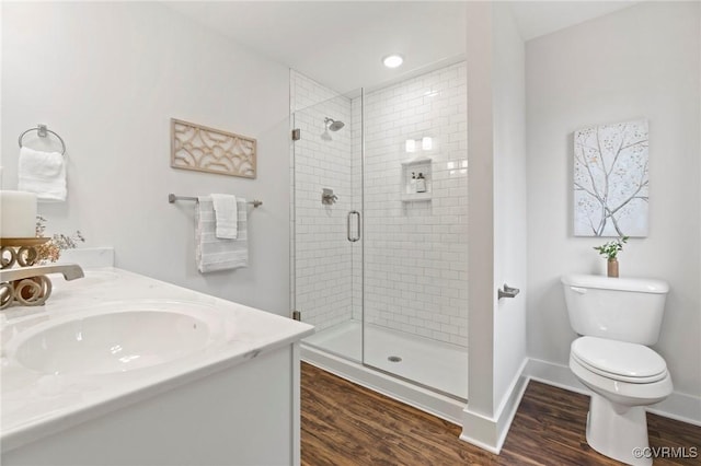 full bath featuring a shower stall, wood finished floors, a sink, baseboards, and toilet