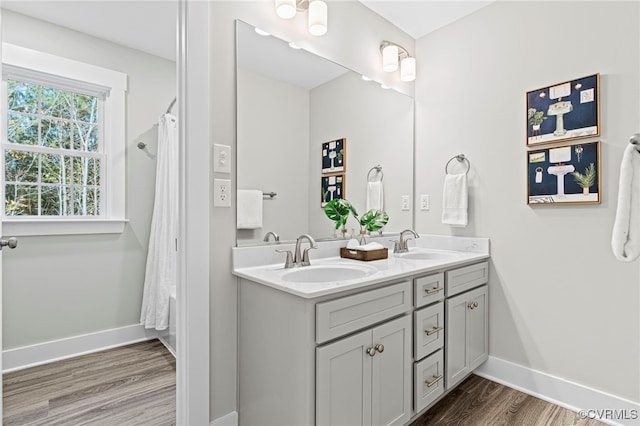 full bathroom featuring baseboards, a sink, and wood finished floors