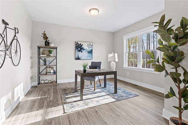 office space featuring baseboards, wood finished floors, and visible vents