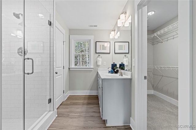 bathroom with vanity, visible vents, baseboards, a spacious closet, and a shower stall