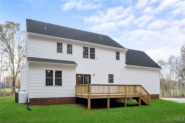 rear view of property featuring a lawn, a deck, and a shingled roof