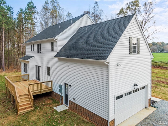 rear view of house with roof with shingles, a wooden deck, and a garage