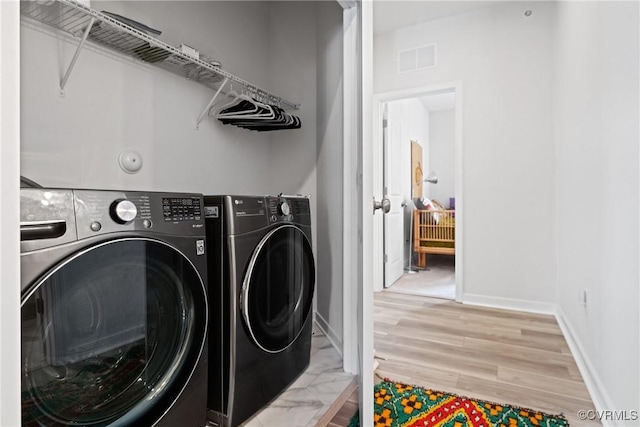 clothes washing area featuring separate washer and dryer, laundry area, light wood-type flooring, and visible vents