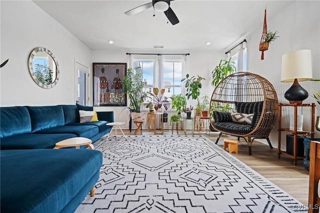 living area with a healthy amount of sunlight, a ceiling fan, wood finished floors, and visible vents