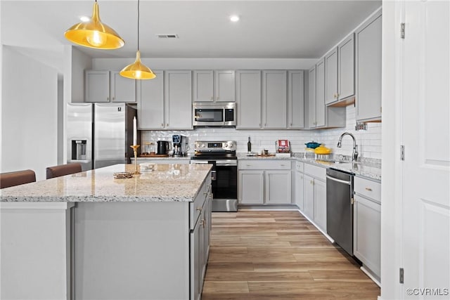 kitchen with visible vents, a kitchen island, a sink, gray cabinetry, and stainless steel appliances