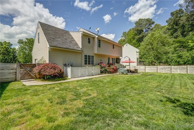 rear view of house with a shingled roof, a yard, a gate, and a fenced backyard