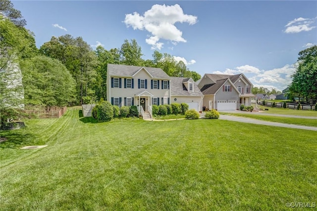 colonial-style house with concrete driveway, a front yard, and fence