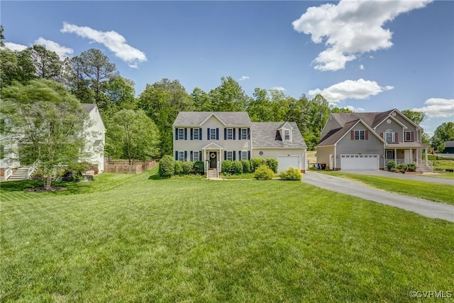 colonial inspired home featuring aphalt driveway, fence, a garage, and a front lawn
