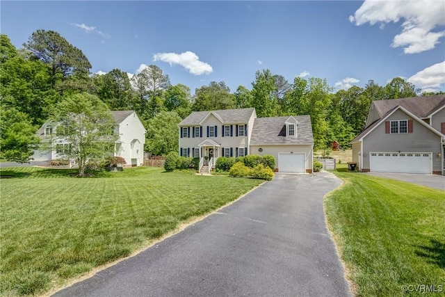 colonial-style house featuring aphalt driveway, a garage, and a front yard