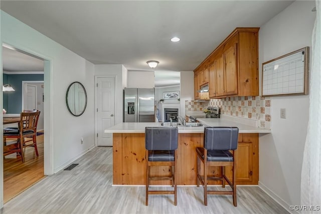 kitchen with stainless steel appliances, visible vents, a peninsula, backsplash, and light countertops