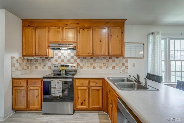 kitchen featuring a sink, brown cabinetry, appliances with stainless steel finishes, under cabinet range hood, and light wood-style floors