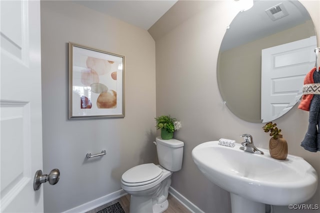 half bath featuring a sink, toilet, baseboards, wood finished floors, and visible vents
