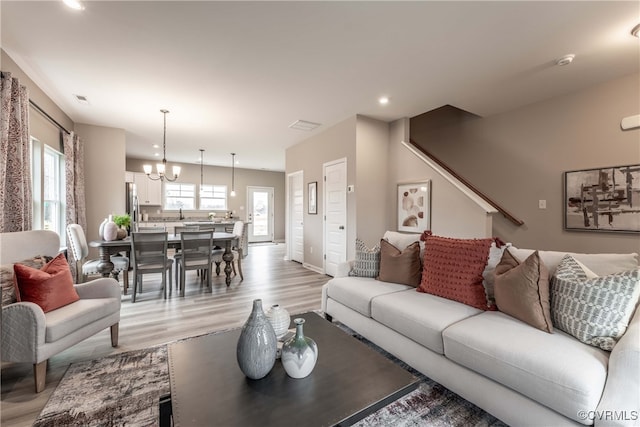 living area featuring light wood-style floors, a wealth of natural light, recessed lighting, and a chandelier