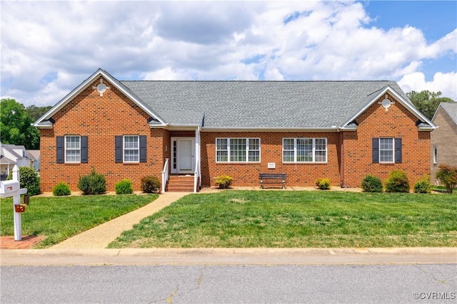 single story home with roof with shingles, a front yard, and brick siding