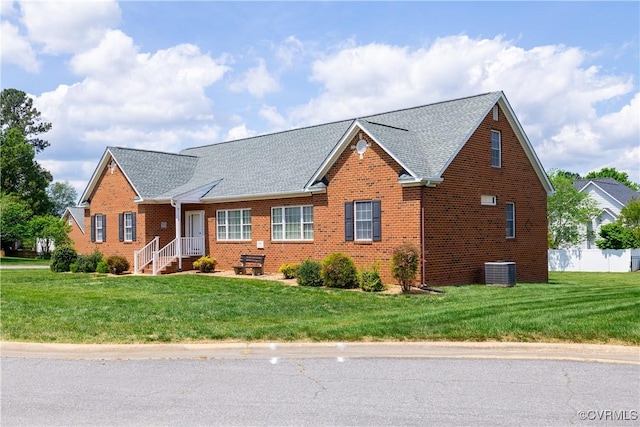 view of front facade with brick siding, cooling unit, a shingled roof, and a front yard