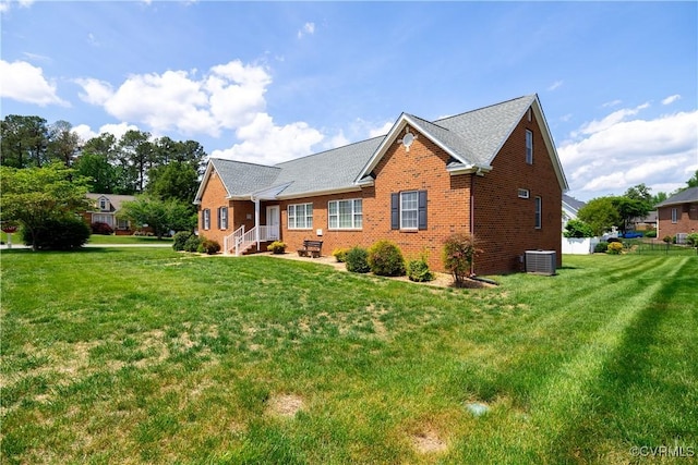 rear view of property with a yard, central AC, and brick siding