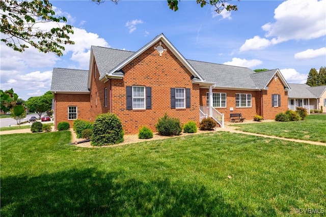 single story home with brick siding, a front yard, and roof with shingles