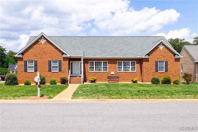 single story home featuring brick siding, a shingled roof, and a front yard