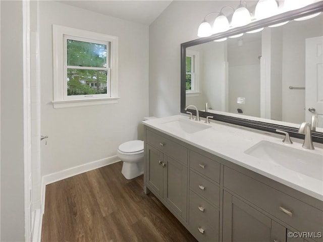 full bath featuring toilet, baseboards, a sink, and wood finished floors