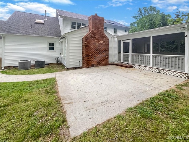 rear view of house with crawl space, a sunroom, a yard, a patio, and a shingled roof