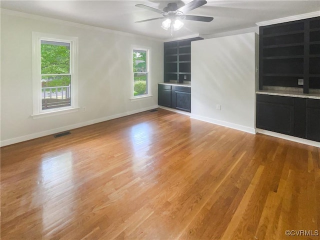 unfurnished room featuring crown molding, baseboards, ceiling fan, and visible vents