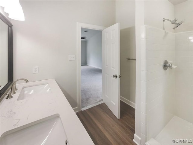 full bathroom featuring tiled shower, baseboards, vanity, and wood finished floors