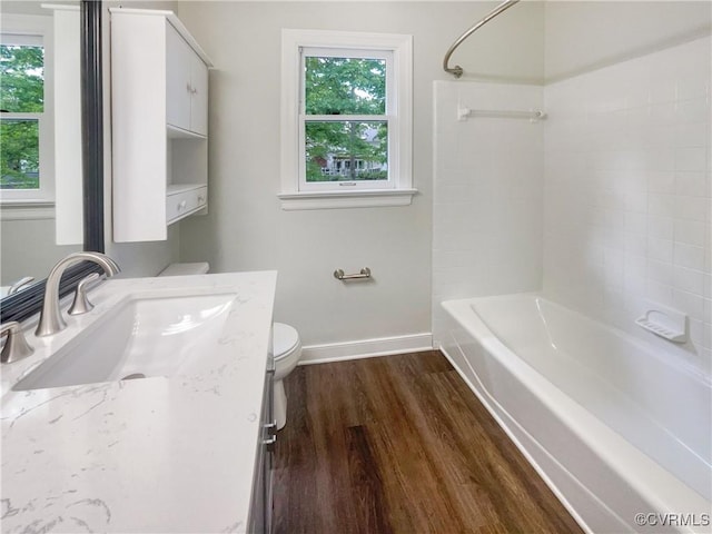 full bathroom featuring toilet, baseboards, a wealth of natural light, and wood finished floors