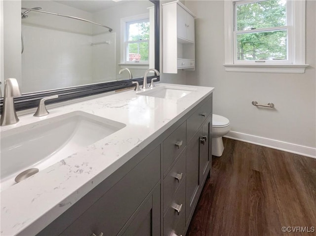 bathroom with toilet, baseboards, a sink, and wood finished floors