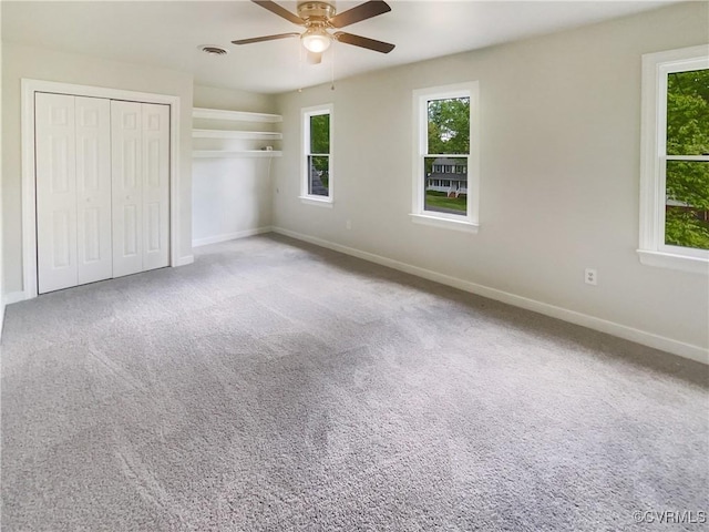 unfurnished bedroom with carpet flooring, a ceiling fan, baseboards, and visible vents
