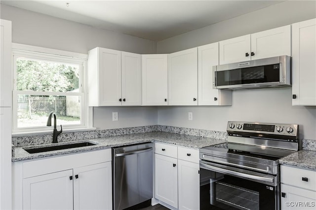 kitchen with a sink, white cabinetry, light stone countertops, and stainless steel appliances
