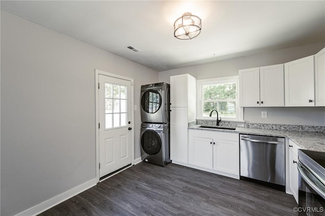 clothes washing area with laundry area, a sink, visible vents, dark wood-style floors, and stacked washer and clothes dryer