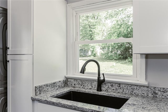 details featuring light stone counters, a sink, and white cabinetry