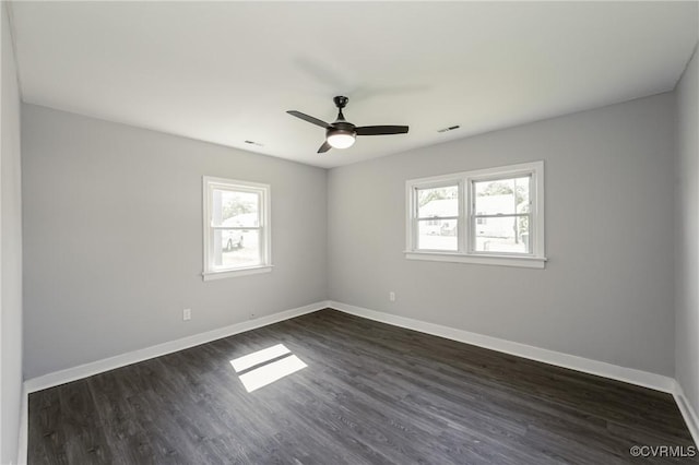 empty room featuring visible vents, baseboards, ceiling fan, and dark wood-style flooring
