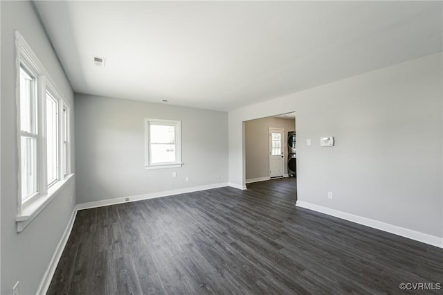 unfurnished room featuring a healthy amount of sunlight, baseboards, and dark wood-style flooring
