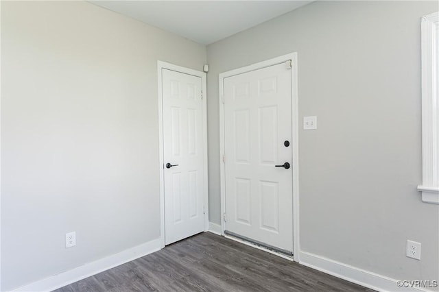 unfurnished room with baseboards and dark wood-style floors