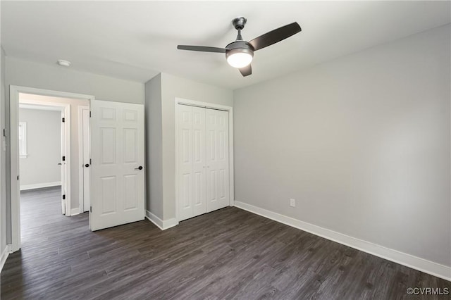 unfurnished bedroom featuring baseboards, a ceiling fan, dark wood finished floors, and a closet