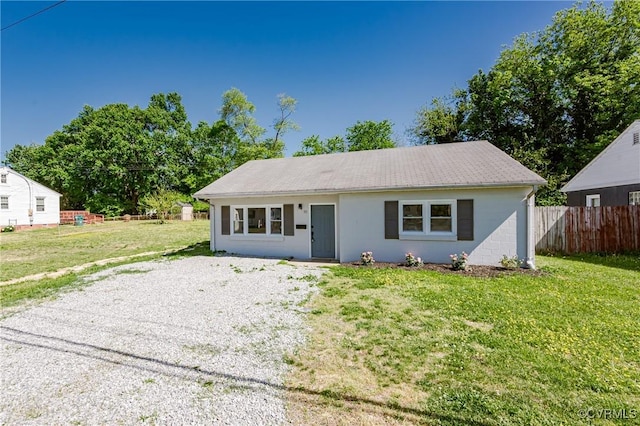 view of front of house with gravel driveway, fence, and a front lawn