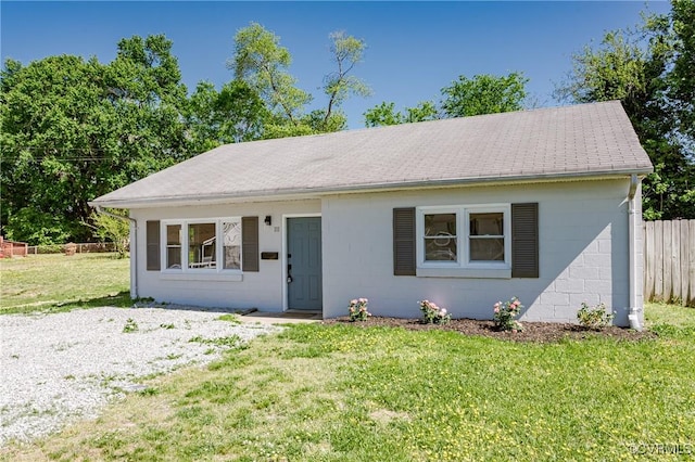 view of front of home featuring concrete block siding, fence, and a front yard