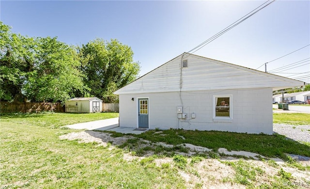 back of property with fence, a storage unit, an outdoor structure, and a lawn