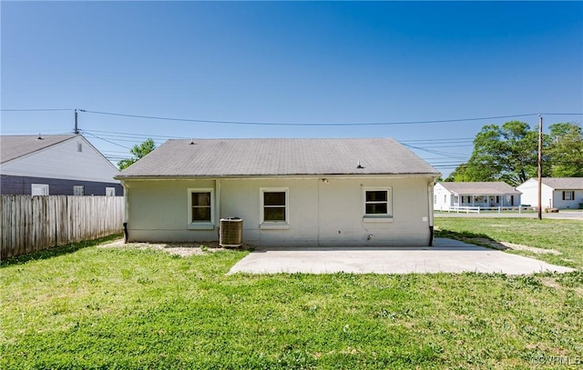 rear view of property with a lawn, a patio area, fence, and central AC