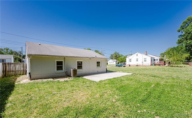 back of property with a lawn, a patio area, central air condition unit, and fence