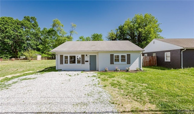bungalow featuring fence, an outbuilding, and a front yard