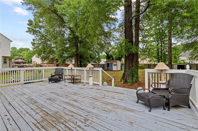 wooden deck featuring a storage unit, an outbuilding, and a fenced backyard
