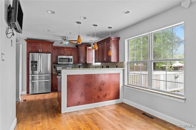 kitchen with appliances with stainless steel finishes, a ceiling fan, baseboards, light countertops, and tasteful backsplash