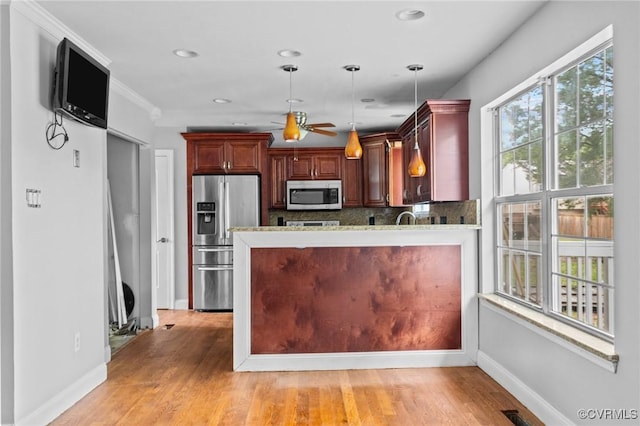 kitchen with appliances with stainless steel finishes, a ceiling fan, baseboards, decorative backsplash, and decorative light fixtures