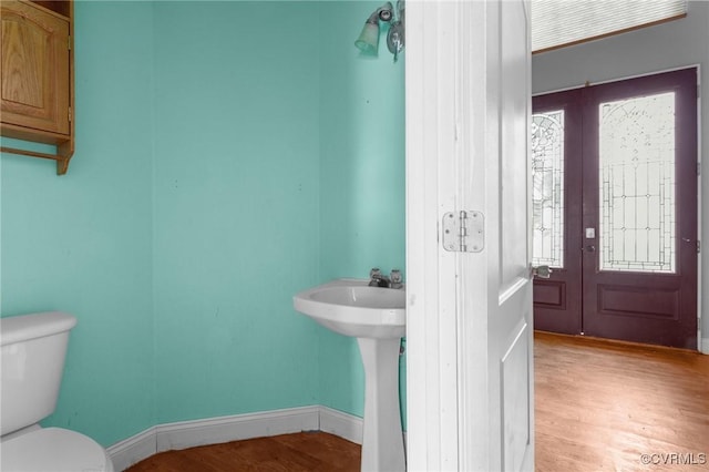 bathroom featuring toilet, baseboards, wood finished floors, and plenty of natural light